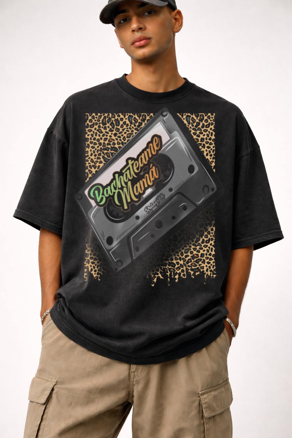 Person wearing a black t-shirt with a cassette tape graphic and 'Bachateame Mama' text. Dominican Shirt, black, Dominican pattern— Heavy Oversized Shirt, Rulay Life design
