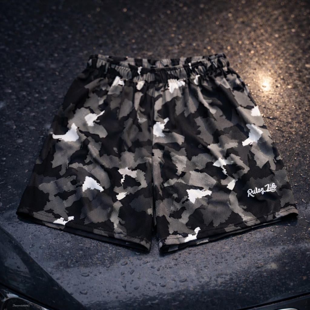 Camouflage shorts with a brand logo on a dark textured surface. black Dominican shorts