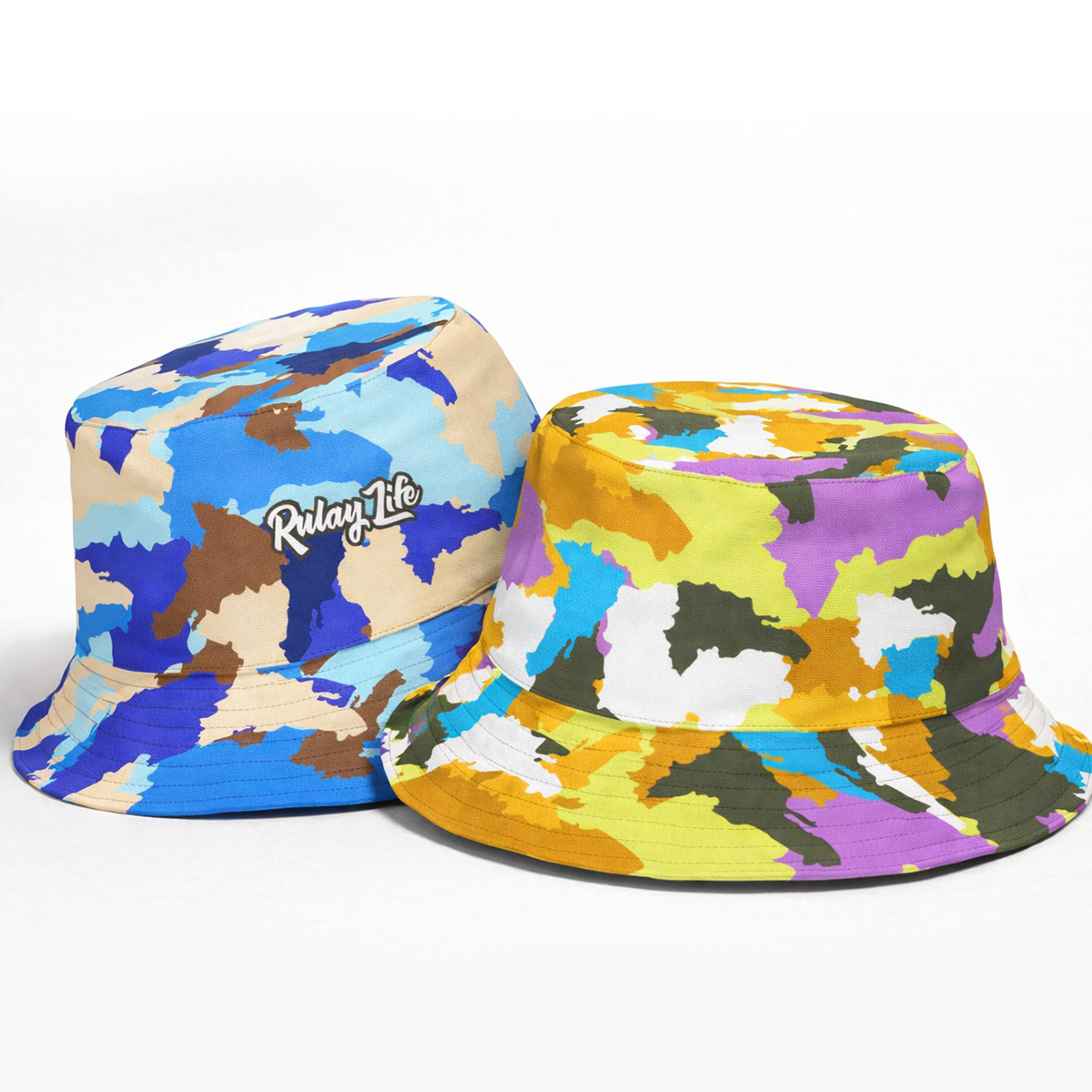 Two colorful bucket hats with a brand logo on a white background. Dominican Camo Reversible bucket hat (Raikou/Winter Soil). Rulaylife.com Dominican Bucket hat