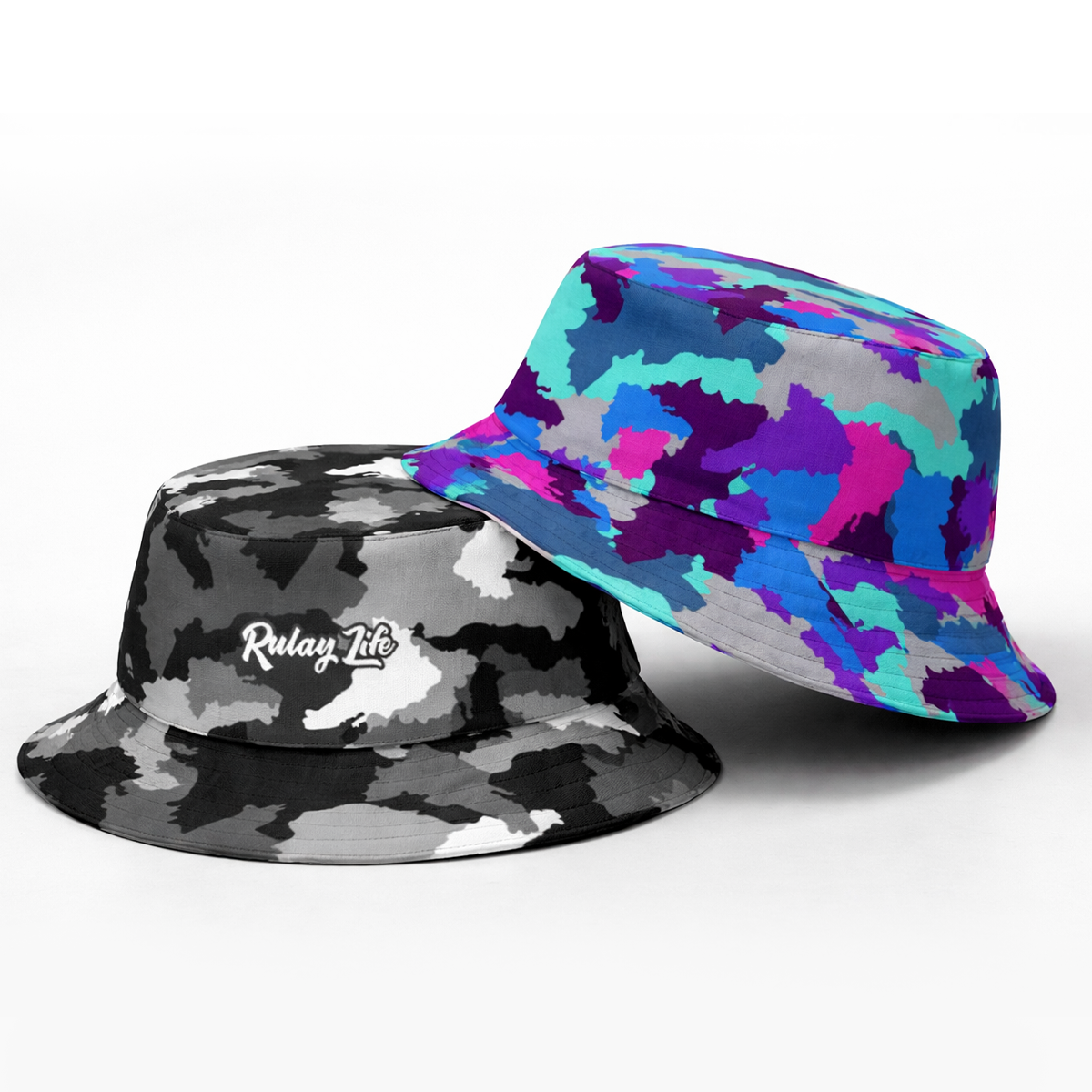 Two bucket hats, one black and gray camouflage and one multicolored, on a white background. Dominican Camo Reversible bucket hat (Black/Amaranth)