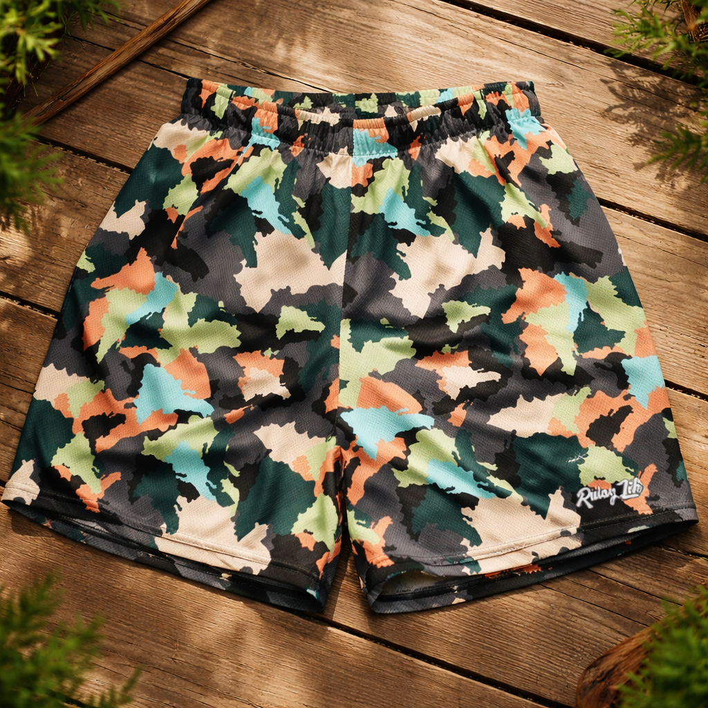 Camouflage-patterned shorts on a wooden surface with greenery around. Dominican shorts